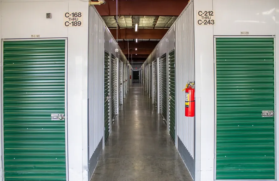Climate-controlled storage hallway with green roll-up doors and wide indoor corridor